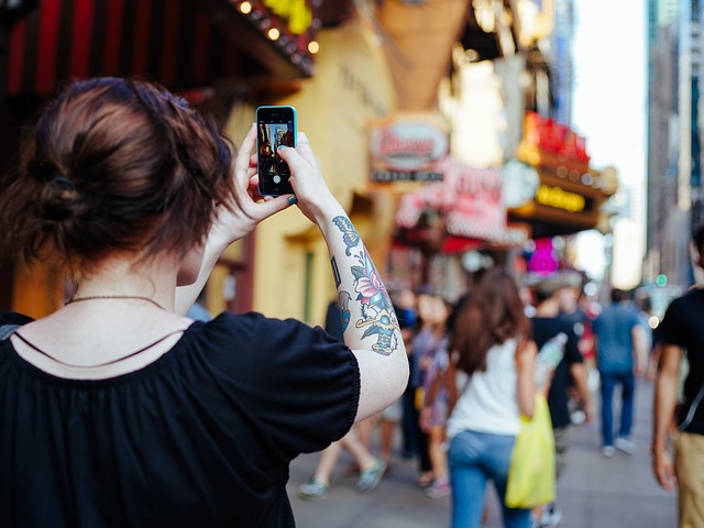 dívka s tetováním fotící rušnou ulici
